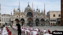 Un ospătar stand printer mesele goale la un restaurant din Piața San Marco din Veneția, Italia