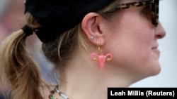 Активистка за правата на абортусот носи обетка на која е прикажана матка. 