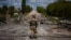 Украинский военный у разрушенного моста в Харьковской области, май 2022 года