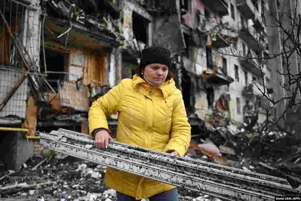 Një grua pastron mbeturinat në një ndërtesë banimi të dëmtuar në rrugën Koshytsa, një periferi të kryeqytetit ukrainas Kiev, që dyshohet se u godit nga një predhë ushtarake, më 25 shkurt 2022.