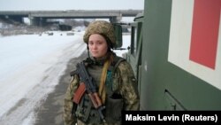 A 21 éves Násztya, az ukrán fegyveres erők orvosa egy katonai mentőautó mellett áll az oroszok által támogatott lázadók és az ukrán erők közti válaszvonal közelében az ukrajnai Donyecki területen lévő Piski falu előtt 2022. január 26-án