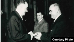 Liderul RPR Gheorghe Gheorghiu Dej, primul dintre cei doi dictatori din vremea comunismului în România, oferind o decorație unui responsabil local la ceremonia de încheiere oficială a colectivizării, 5 martie 1962. În planul secund, Nicolae Ceaușescu, succesorul la putere. Arhivele Naționale.