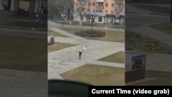 Житель Херсона, размахивающий украинскими флагами перед российскими танками, припаркованными на центральной площади города