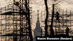 Градежните работници работат на скелиња во руската престолнина со зградата на државниот универзитет во Москва во позадина. (фотографија од датотека)