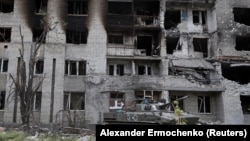 A Russian tank sits in front of a damaged apartment building in the town of Popasna in Ukraine's Luhansk region on May 26. 