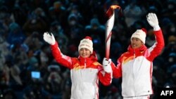 Динигеер Йиламуцзян (солдо) жана Цзяфэн Чжао (оңдо) Олимпиада отун көтөрүп бара жатышат. Бээжин, 4-февраль, 2022-жыл.