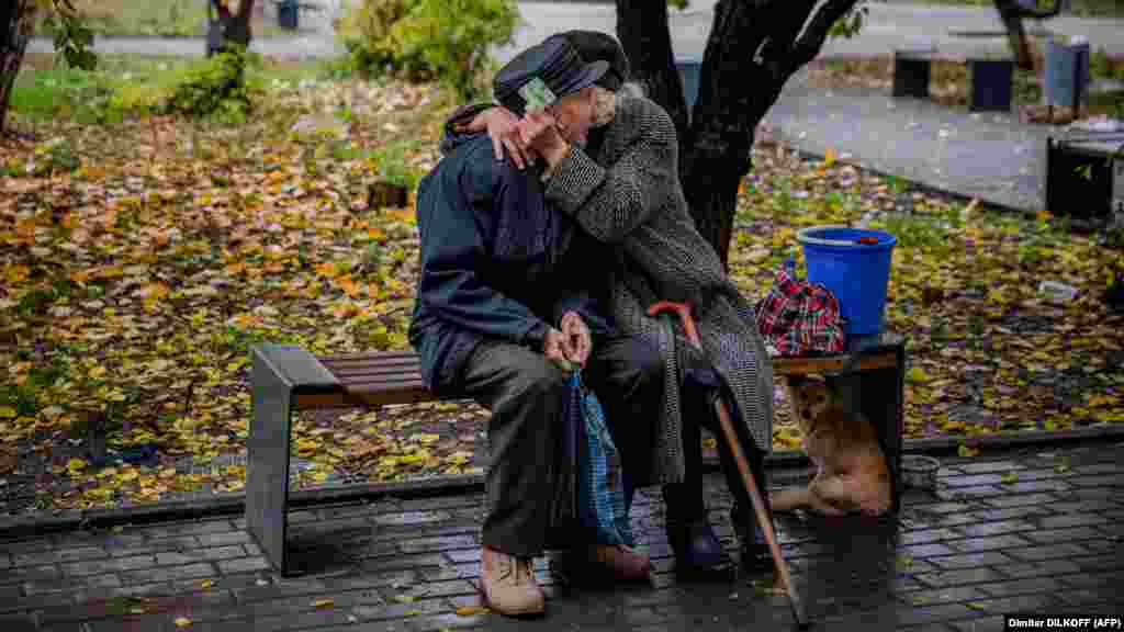Egy idős házaspár ölelkezik egy padon a frontvonalon fekvő Bahmutban a lövések szünetében 2022. október 27-én. A kelet-ukrajnai régiót hónapok óta támadják az orosz csapatok