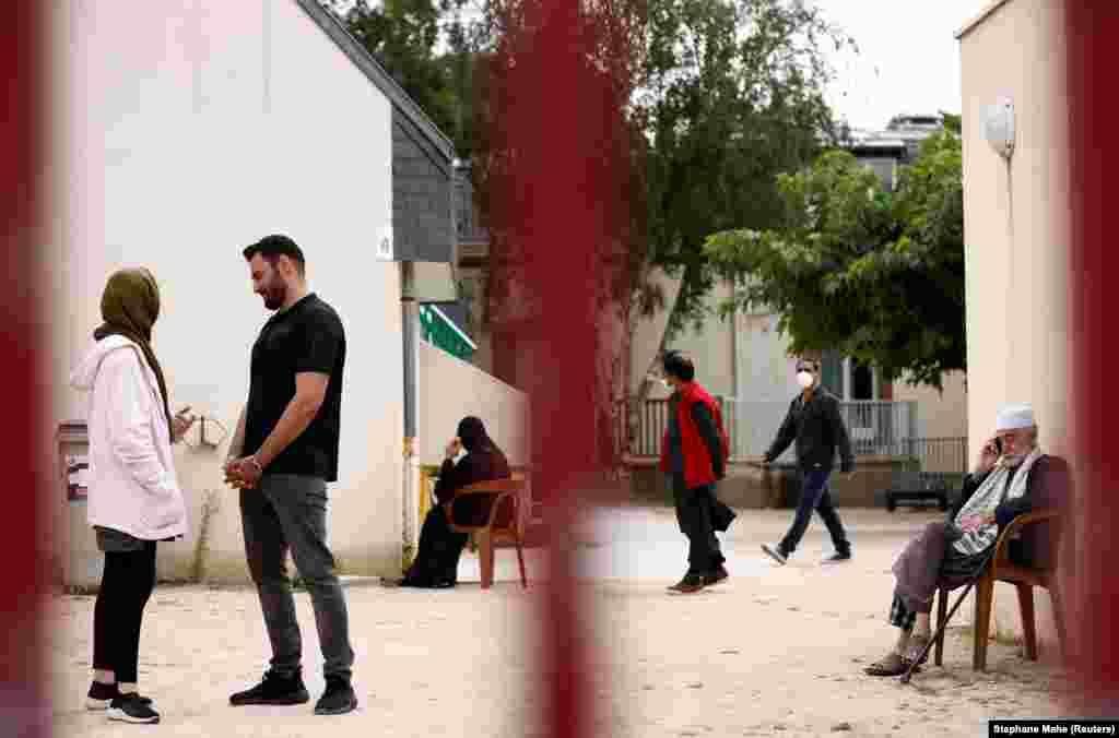 Refugiații afgani Asma Halimi, în vârstă de 25 de ani, și Mohammad Omer Aiuby, în vârstă de 29 de ani, stau de vorbă în curtea centrului de primire Razay din Piriac-sur-Mer din Franța.