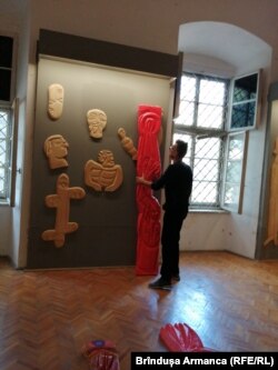 Stâlpii au invadat și spațiul expoziției de la etaj. Florin Arhire ridică la verticală un stâlp culcat de curatoarea Simona Abagiu