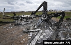Український сапер шукає нерозірвану вибухівку серед потрощених останків знищеного російського гелікоптера. Гостомель, околиця Києва, 18 квітня 2022 року