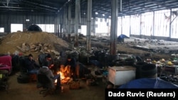 Boszniában, Velika Kladusa mellett, egy elhagyott gyárépületben próbálnak migránsok melegedni 2021. január 31-én.