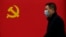 Чоловік у масці на тлі прапора Комуністичної партії Китаю, Ухань, 31 березня 2020 року