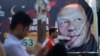 Pakistani men sit near a poster of Pakistan's cricketer-turned-politician and head of the Pakistan Tehreek-e Insaf (Movement for Justice) party Imran Khan, in Islamabad on July 30.