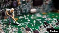 Інсталяція: робітник з лопатою на електронній платі 