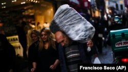 Një burrë mban mallra në shpinë në një zonë tregtare në Stamboll, Turqi, të martën, 2 nëntor 2021. Shumë konsumatorë turq po përballen me vështirësi në rritje pasi çmimet e ushqimeve dhe mallrave të tjera janë ngritur në vitet e fundit.