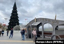 Oameni așteptând transportul public la stația din Piața Suvorov de la Tiraspol, unde deja de la mijlocul lunii noiembrie este amenajat bradul de Craciun.
