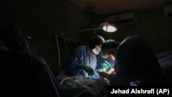 Dr. Abeer Al-Gharbawi, majtas, duke operuar një pacient nën dritën e një llambe me bateri, gjatë një ndërprerjeje rryme në spitalin Shifa, në Qytetin e Gazës, më 4 korrik 2025.