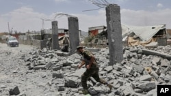 یک سرباز حوثی‌های یمن در حال عبور از ویرانه‌ای در صنعا که گفته می‌شود هدف حمله ارتش آمریکا قرار گرفته است 