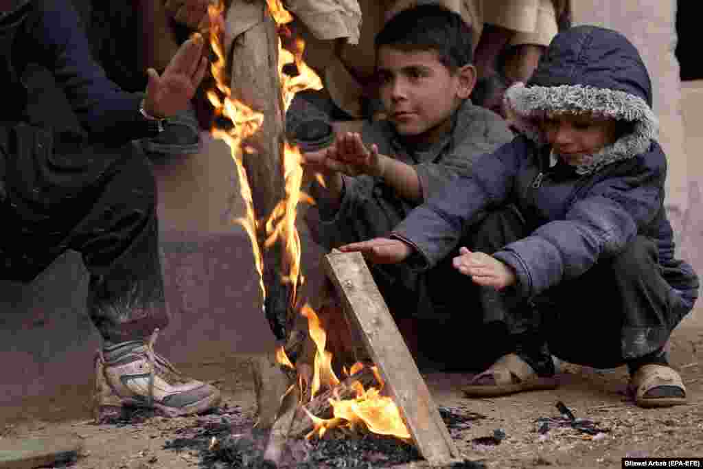 Fëmijët ngrohen pranë këtij zjarri të ndezur në Peshavar të Pakistanit. (epa-EFE/Bilawal Arbab)