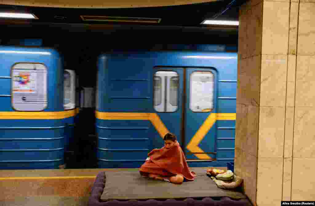 Një vajzë e mbuluar me batanije pranë një treni, gjatë strehimit në një stacion metroje në Kiev, më 8 korrik.