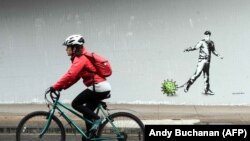 Egy kerékpáros elhalad egy koronavírus által inspirált graffiti mellett Glasgow-ban, 2020. április 4-én