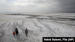 یک خانواده ایرانی در حال گذر از بستر خشک دریاچه ارومیه در اردیبهشت ۱۳۹۰