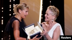 Cannes, Franța, 17 iulie 2021. Regizoarea Julia Ducournau primind trofeul Palme d'Or pentru filmul "Titane" de la Sharon Stone. REUTERS/ Eric Gaillard TPX IMAGES OF THE DAY