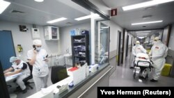 Hordágyas mentősök egy koronavírusos beteg szállítására várnak egy brüsszeli klinikán 2020. október 28-án.
