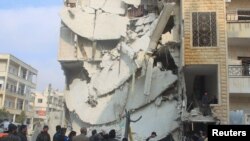 Орусиянын аба соккуларынан кыйрады делген Идлиб шаарындагы имараттардын жанындагы эл. Сирия, 20-декабрь, 2015-жыл