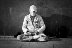 عضوی یکی از فرقه‌های چینی در حالی‌که در میانه بحران ناشی از همه‌گیری کرونا در پیاده‌رویی در شهر قدیم تایپه، مشغول مراقبه است