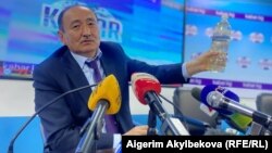 Глава Минздрава Алымкадыр Бейшеналиев на пресс-конференции демонстрирует бутылку с отваром иссык-кульского корня. Бишкек. 16 апреля 2021 года.
