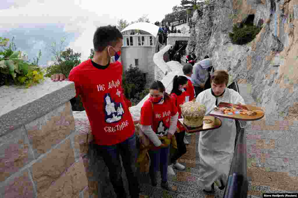 Свештеник брзо минува низ маскирани верници на гробот на Свети Василиј во Никшиќ, Црна Гора, на 12 мај.