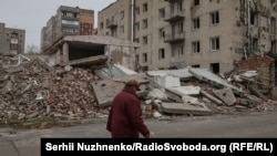 Місцева жителя йде на фоні зруйнованої будівлі у Покровську, Донецька область, Україна, Листопад 2024 року