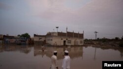 Pakistanci stoje ispred poplavljene džamije u Nowshera, na severozapadnom delu provincije Khyber-Pakhtunkhwa, 1 avgust 2010