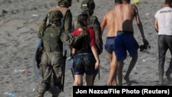 Izbjeglice i migranti pod pratnjom vojske nakon što su preplivali iz Maroka u špansku regiju Seutu, na afričkom kontinentu, 19. maj 2021. 