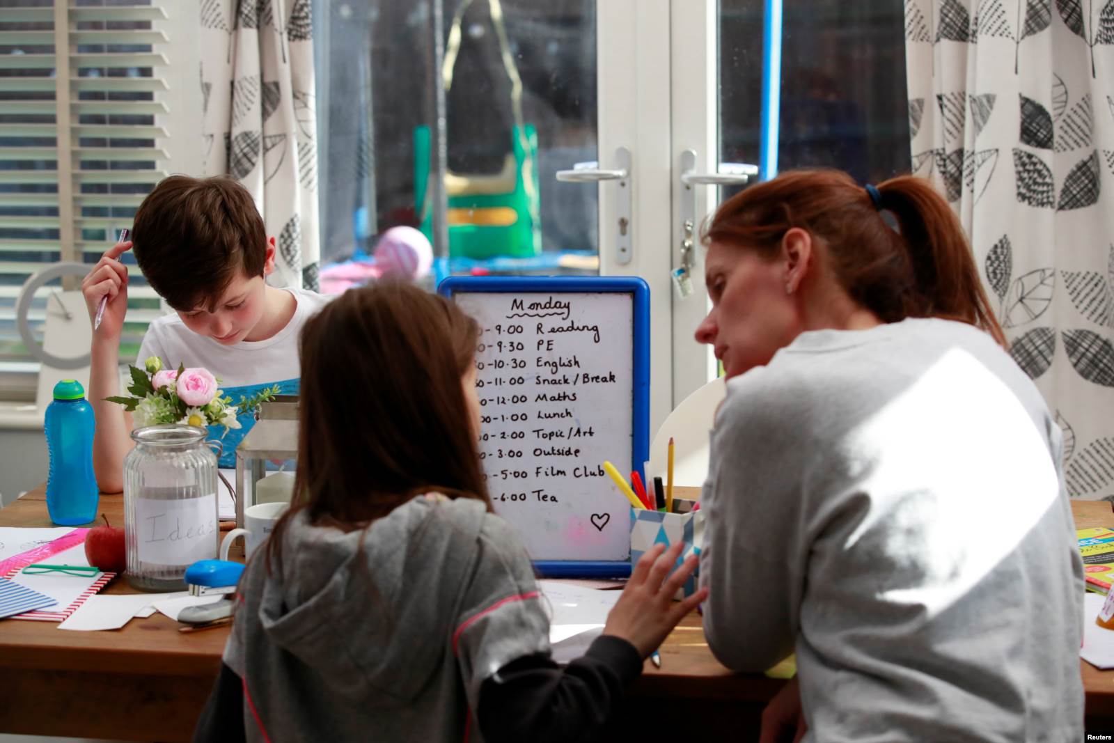 Një nënë duke iu ndihmuar fëmijëve të saj për t’u përgatitur për mësim nga shtëpia