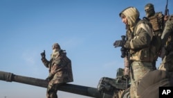 Sirijski pobunjenici stoje zaplijenjenom oklopnom vozilu sirijske vojske u predgrađu Hame, Sirija, 3. decembra 2024.