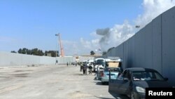 Egyiptomi önkéntesek nézik a rafahi átkelőnél a palesztin oldalról felszálló füstöt, miközben a segélyszervezetek az átkelő újranyitására várnak 2023. október 17-én