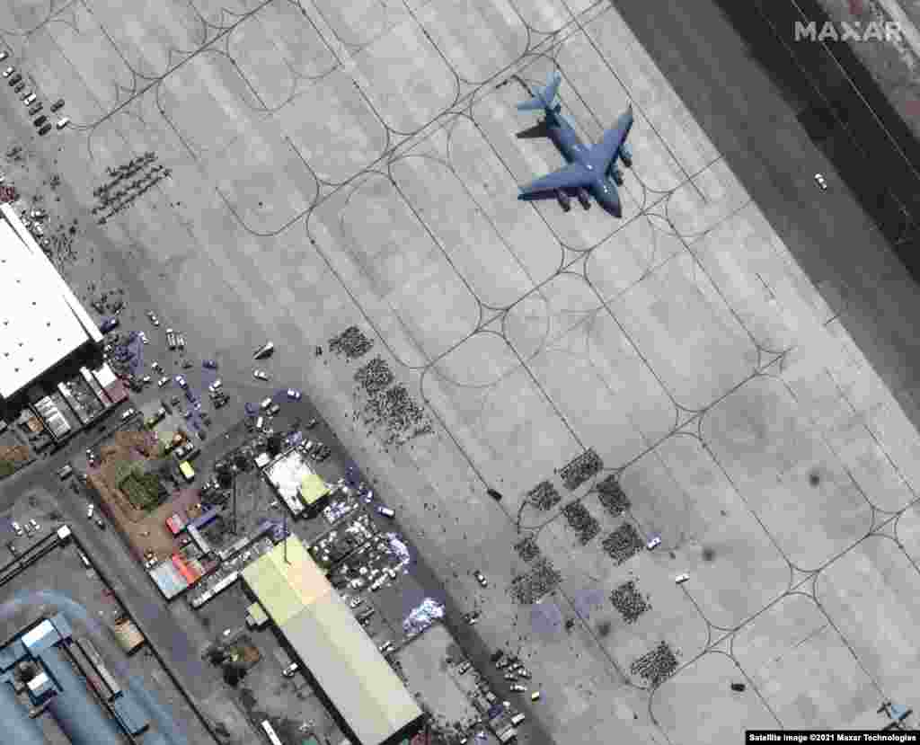 Mulțimi de oameni așteaptă să fie îmbarcați pe Aeroportul Internațional Hamid Karzai din Kabul. Un avion de transport C-17 este gata de decolare. 23 august 2021