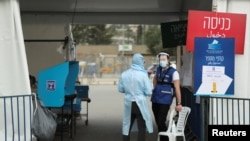 Izborni službenici koji nose zaštitnu opremu stoje na posebnom mobilnom biračkom mjestu za Izraelce u karantinu ili zaražene korona virusom dok Izraelci započinju glasanje na opštim izborima, u Jeruzalemu 23. marta 2021. 