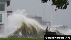 Жаңы Орлеандын тургуну жээктен көтөрүлүп жаткан толкунду сүрөткө тартып жатат. 29-август, 2021-жыл. 