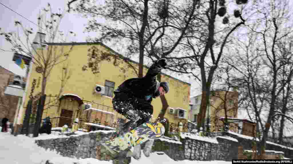 Чоловік катається на сноуборді на Андрієвському узвозі, Київ, 11 лютого 2021 року