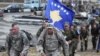 Kosovo -- Two US soldiers walk in front of a Kosovo national flag being carried by Kosovo Security Force (KSF) members during a march close to the town of Vushtri, October 17, 2015