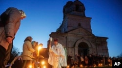 Поп Сергей Зезул согушта талкаланган чиркөөнүн алдында Пасха жөрөлгөсүн жасап жатат. Украинанын Лукашевка кыштагы. 20-апрель, 2025-жыл