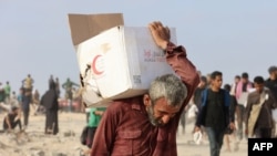 Një burrë duke mbajtur një kuti me ndihma përgjatë rrugës al-Rashid në Jabalian perëndimore, më 22 qershor 2025.