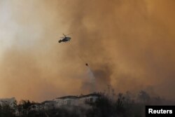 Vatrogasni helikopter ispušta vodu kako bi ugasio požar koji se približava naselju u blizini sela Cokertme u regiji Bodrum 3. avgusta 2021.