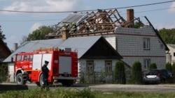 Një polic qëndron në rrugë, ndërsa zjarrfikësit punojnë mbi çatinë e shkatërruar të një shtëpie në Wyryki, Lublin, Poloni, më 10 shtator 2025.