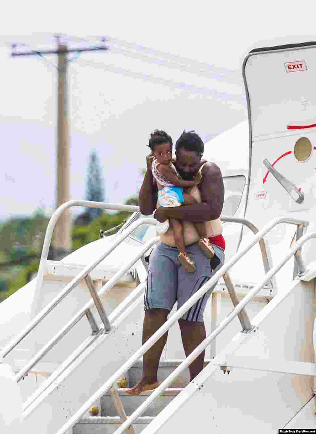 Az USA-ból visszatoloncolt menekültek hagyják el a Haiti fővárosában, Port au Prince-ben leszálló repülőgépet szeptember 19-én