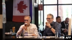Britanski premijer Keir Starmer (desno) i kanadski premijer Mark Carney piju pivo u pubu Royal Oak u Ottawi, Kanada, 14. juna 2025. godine dok na televiziji gledaju finalnu hokejašku utakmicu Stanley Cupa, uoči samita lidera G7.