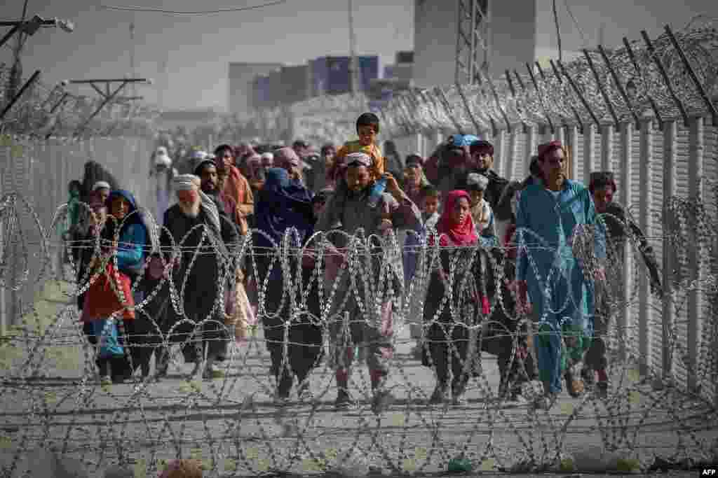 Afganistanci koji bježe iz svoje domovine usred preuzimanja talibana hodaju uz ograde dok 24. augusta stižu u Pakistan preko graničnog prelaza u Chamanu.